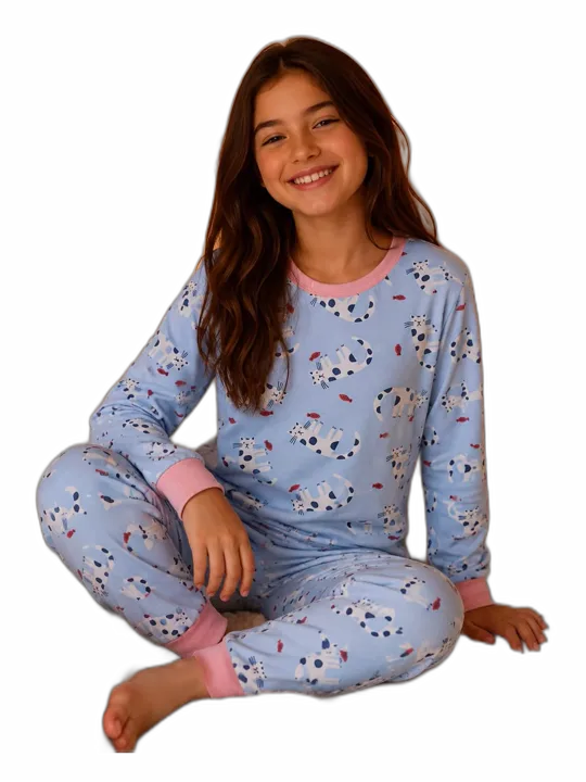 Menina sentada na cama de pijama infantil azul com estampa de gatinhos